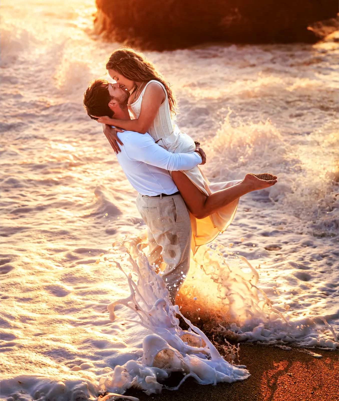 Groom lifting his partner into a kiss in the golden surf on a Carmel beach, photographed by Manny Espinoza